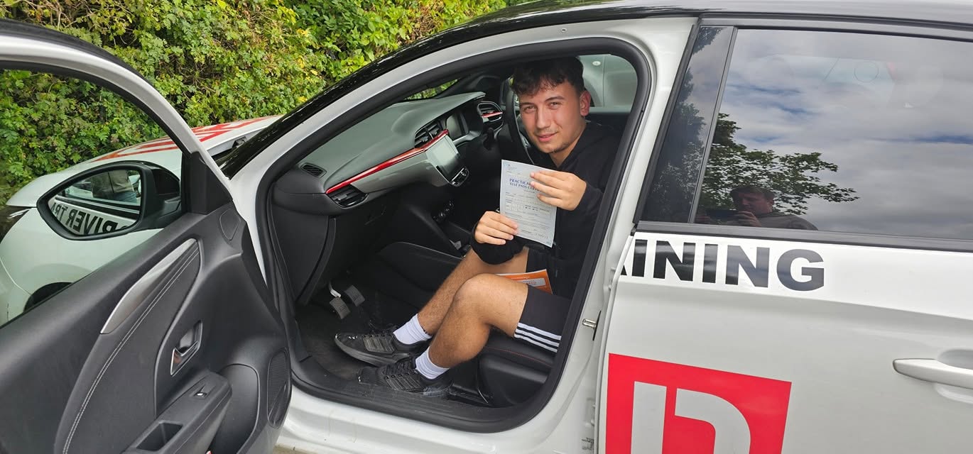 A Worcester learner in the driving school car holding their pass certificate