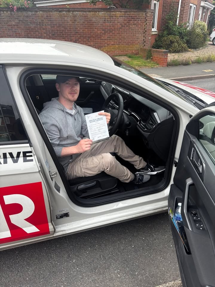 A learner sitting in the driving school car celebrating their driving test pass